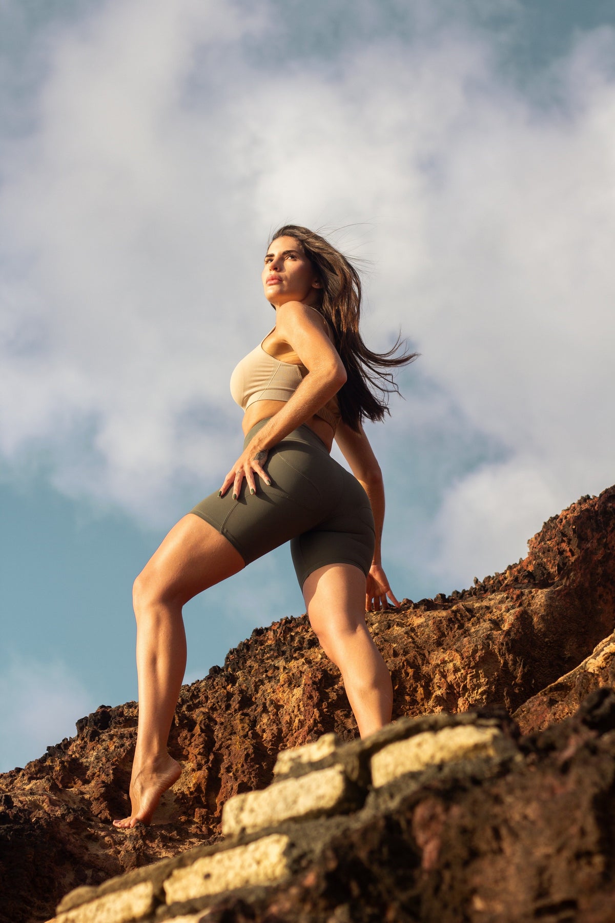 Mulher usando top postural bege Alignmed sob a roupa do dia a dia, sem volume nem fivelas aparentes nas costas